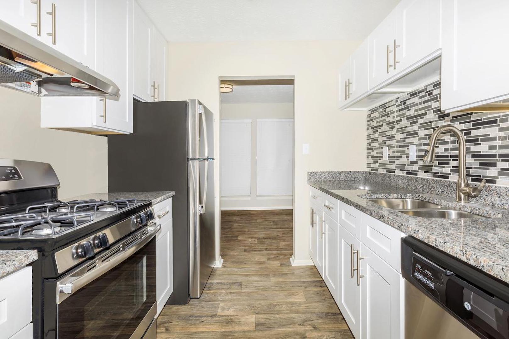 kitchen with upgraded countertops, dishwasher, refrigerator and hardwood finish flooring