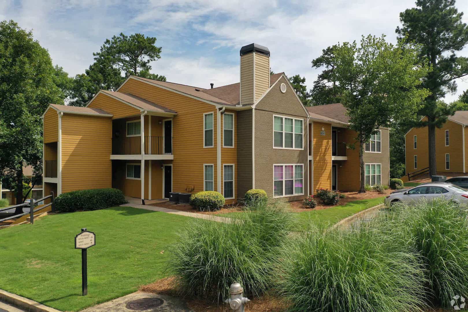 grassy area and beautiful landscape surrounds two toned apartment building