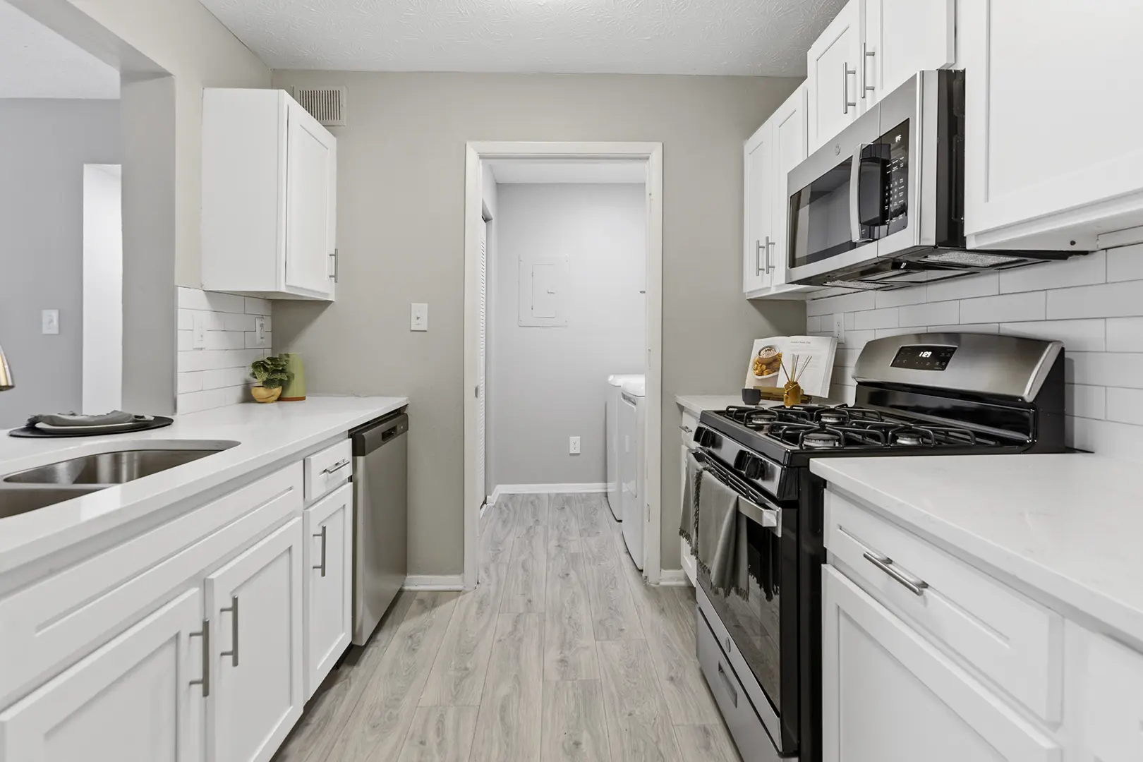 newly renovated kitchen with hardwood finish flooring open to laundry room