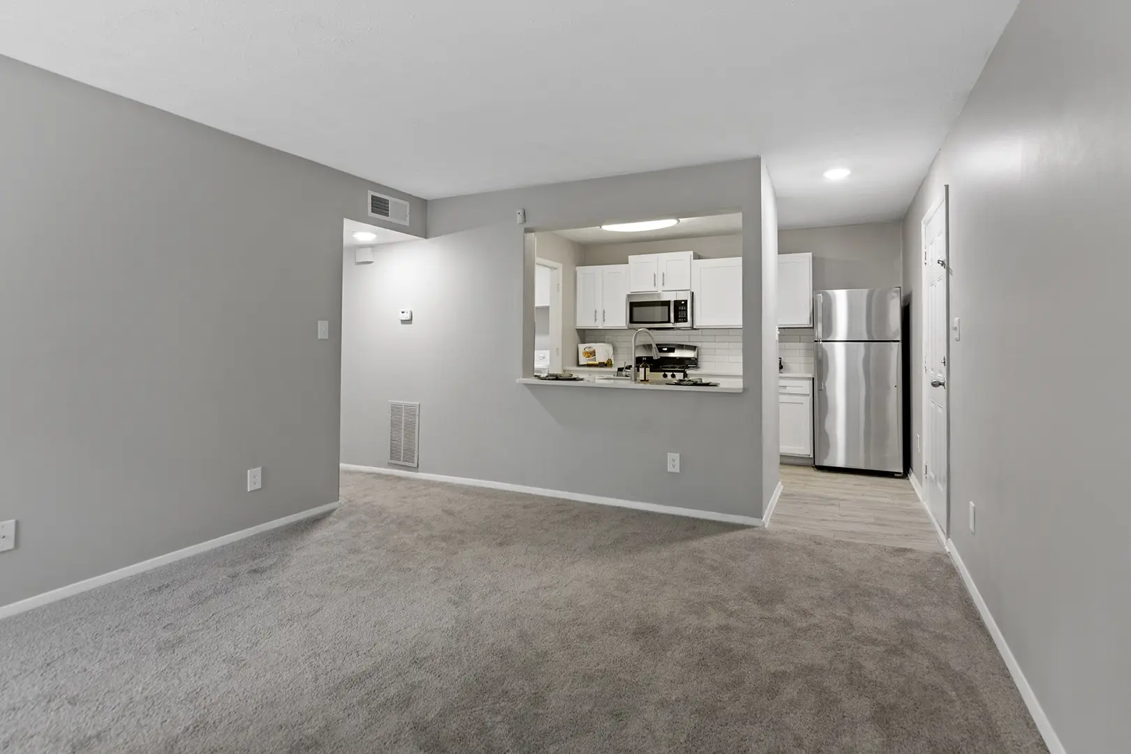 carpeted living room opening to kitchen with breakfast bar